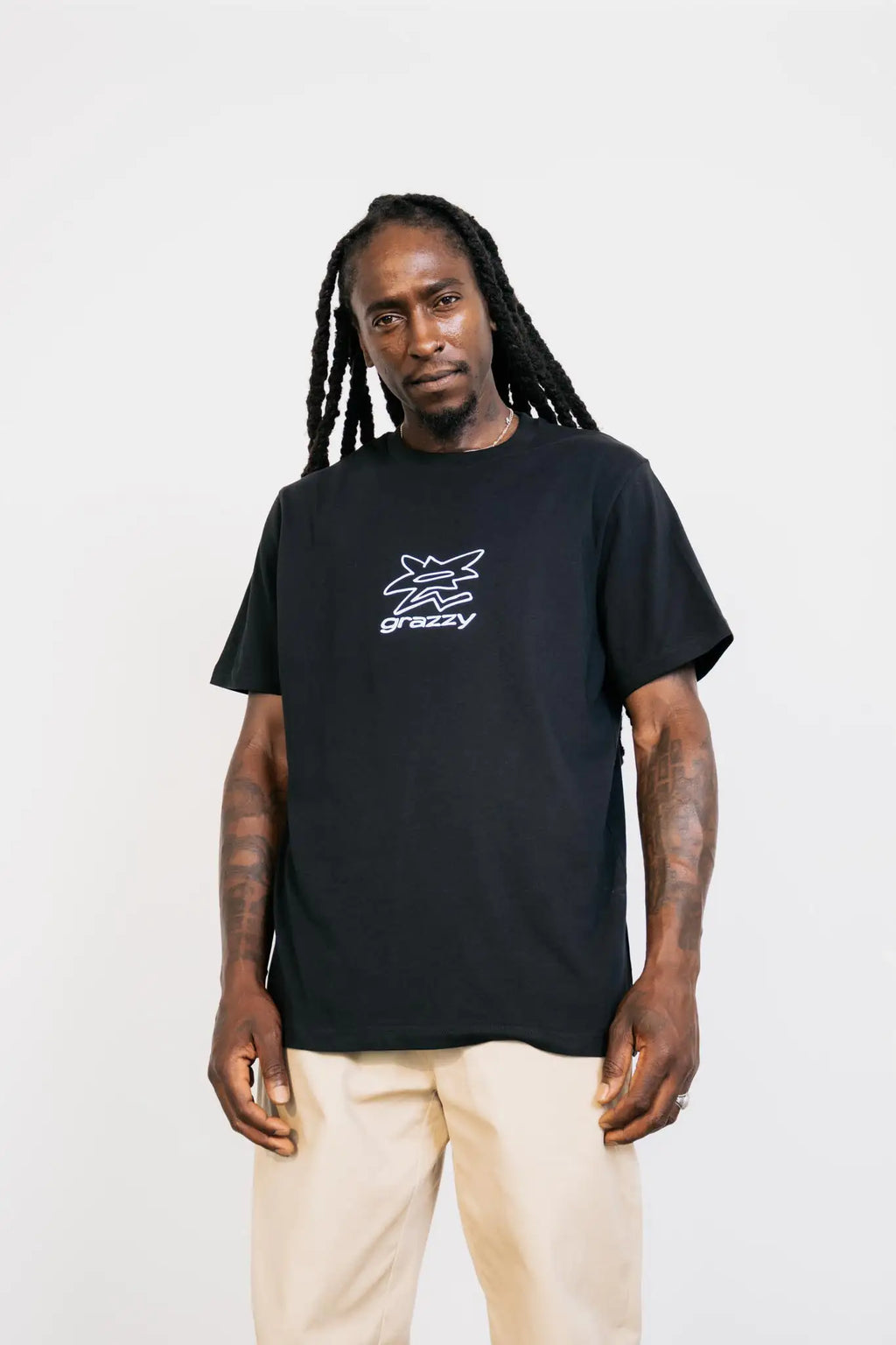 Front view of model in studio wearing the grazzy Symbol t-shirt in the Black colorway, featuring a white flower-like graphic logo mark on the chest.