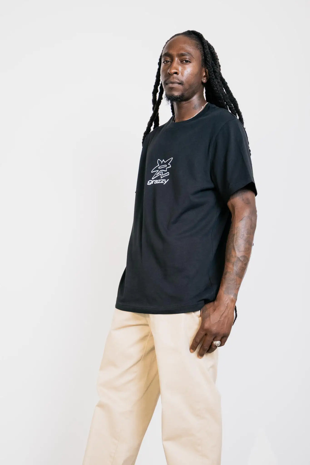 Model in studio wearing the grazzy Symbol t-shirt in the Black colorway, featuring a white flower-like graphic logo mark on the chest.