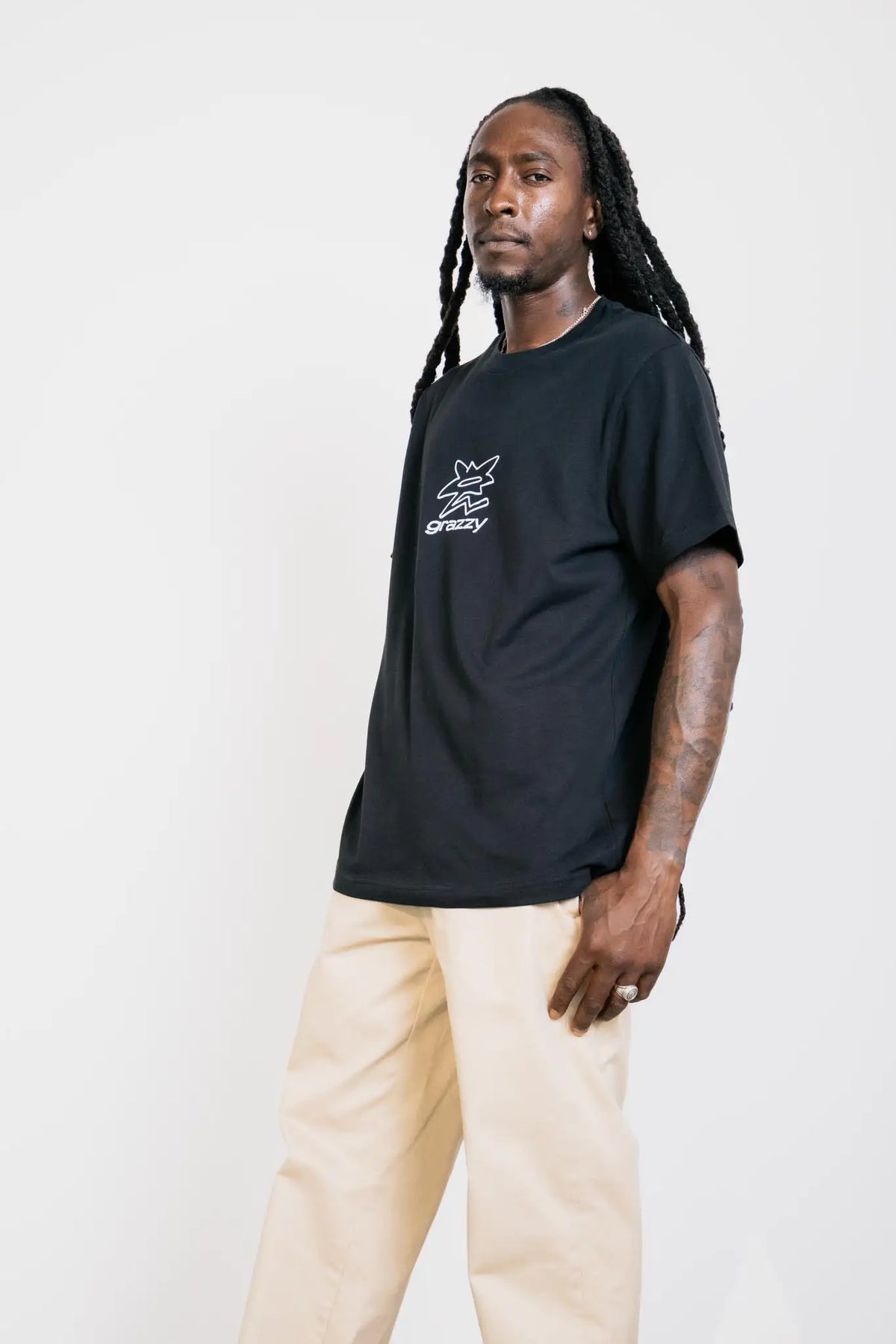 Model in studio wearing the grazzy Symbol t-shirt in the Black colorway, featuring a white flower-like graphic logo mark on the chest.