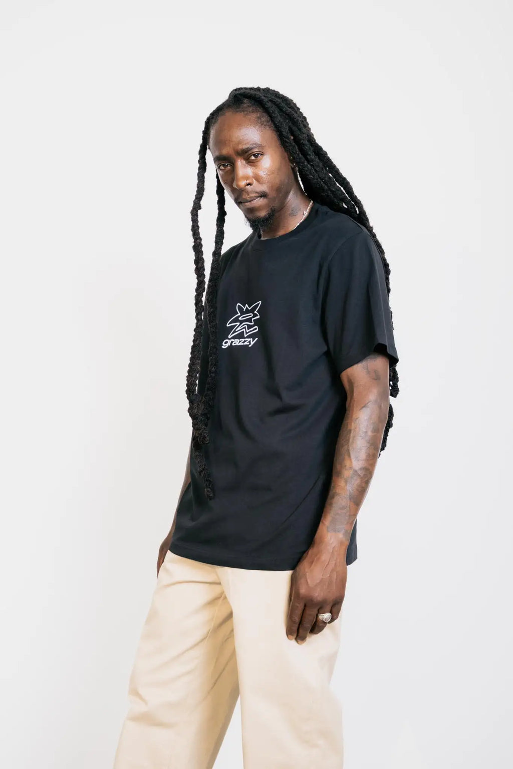 Model in studio wearing the grazzy Symbol t-shirt in the Black colorway, featuring a white flower-like graphic logo mark on the chest.
